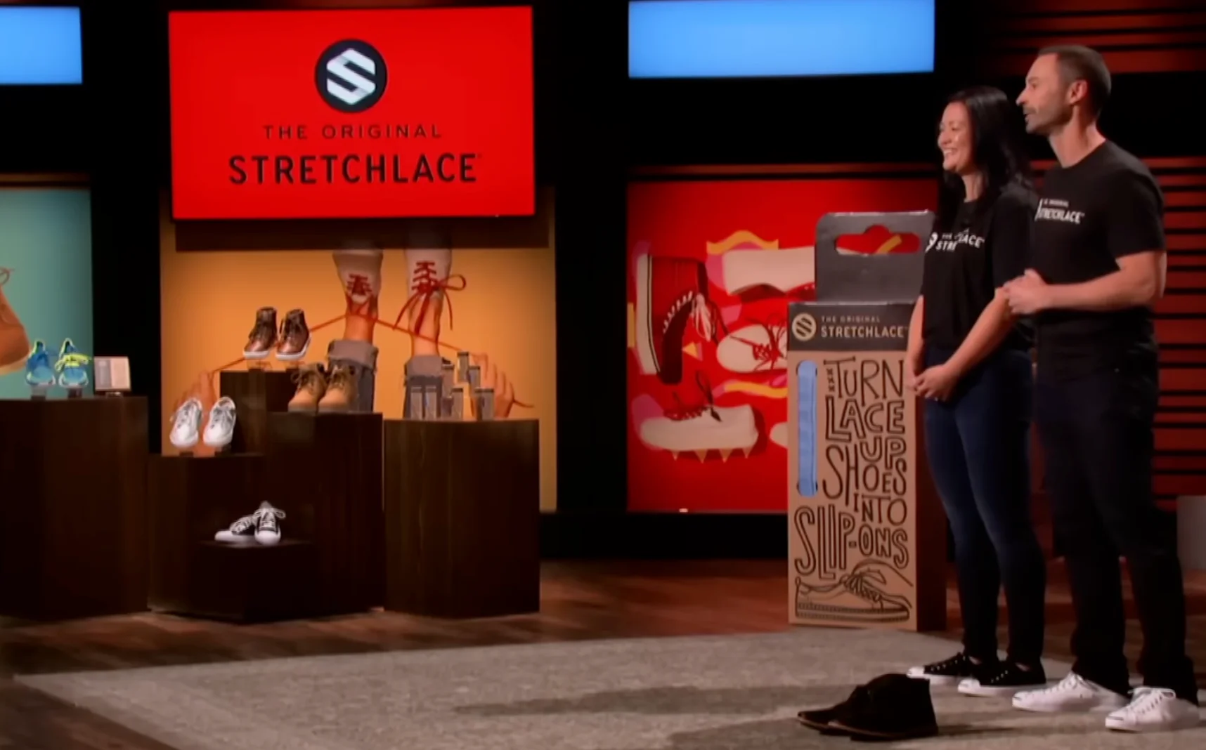 David and Jamie Montz on the Shark Tank set, standing in front of The Original Stretchlace branding with a Stretchlace product display, holding their packaging.